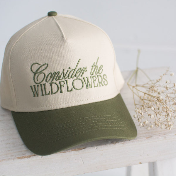 Beige and green cap with 'Consider the Wildflowers' text on a white surface.