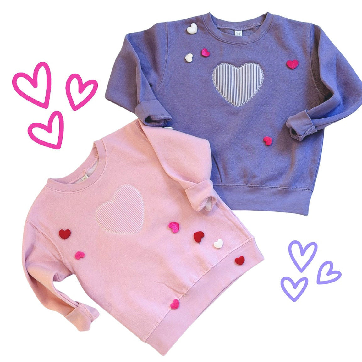Two children's sweatshirts, one pink and one blue, with heart designs on a white background.